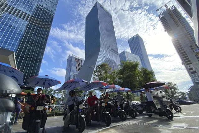 Men on electric bikes wait for riders near the Evergrande headquarters, center, in Shenzhen, China, Friday, September 24, 2021. (Photo by Ng Han Guan/AP Photo)