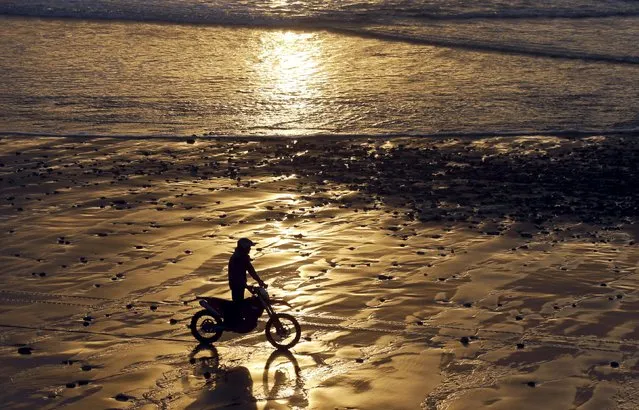A man rides a motorcycle on a beach along the Atlantic Ocean coast at sunset in Cap Ferret, southwestern France, February 19, 2016. (Photo by Regis Duvignau/Reuters)
