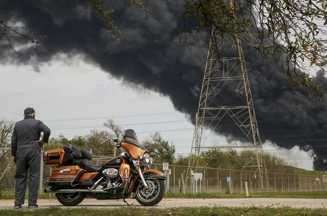 Bruce Bechtel, 64, stands next to his 2008 Harley-Davidson Ultra as he watches the plume of smoke caused by the petrochemical fire at the Intercontinental Terminals Company during his lunch break Monday, March 18, 2019, in Deer Park, Texas. The large fire at a Houston-area petrochemicals terminal will likely burn for another two days, authorities said Monday, noting that air quality around the facility was testing within normal guidelines. (Photo by Godofredo A. Vasquez/Houston Chronicle via AP Photo)