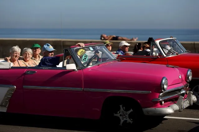 Tourists ride in a vintage car at the seafront Malecon in Havana, March 15, 2016. (Photo by Alexandre Meneghini/Reuters)