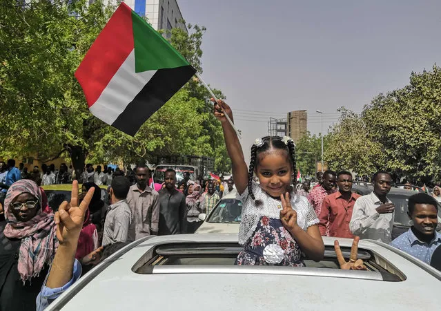 A Sudanese girl flashes the victory sign and holds the national flag during a rally near the military headquarters in the capital Khartoum on April 11, 2019. The Sudanese army is planning to make "an important announcement", state media said today, after months of protests demanding the resignation of longtime leader President Omar al-Bashir. Thousands of Khartoum residents chanted “the regime has fallen” as they flooded the area around army headquarters where protesters have held an unprecedented sit-in now in its sixth day. (Photo by AFP Photo/Strimger)