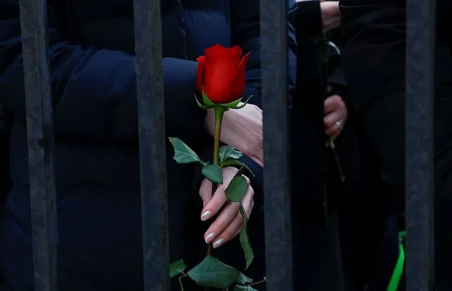 A person holds a rose while standing behind a barrier near the Borisovskoye cemetery during the funeral of Russian opposition politician Alexei Navalny in Moscow, Russia, on March 1, 2024. (Photo by Reuters/Stringer)