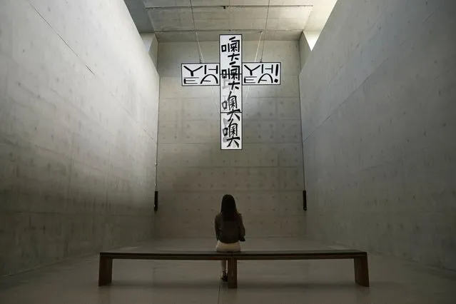 A woman looks at the artwork “Crucified TVs – Not a Prayer in Heaven” created by South Korea artist Chang Young-hae, inside the “M+” visual culture museum during a media preview in the West Kowloon Cultural District of Hong Kong, Thursday, November 11, 2021. (Photo by Kin Cheung/AP Photo)