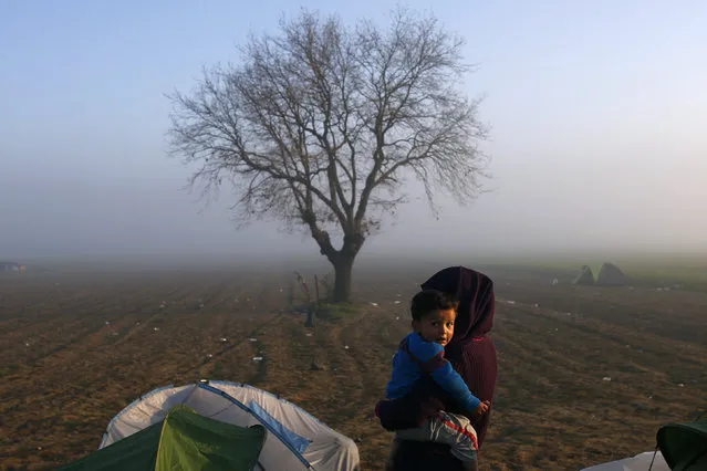 A woman holds a child at a makeshift camp for migrants and refugees at the Greek-Macedonian border near the village of Idomeni, Greece, March 31, 2016. (Photo by Marko Djurica/Reuters)