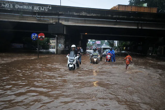 Motorbikes try to pass through water in a flooded area after torrential rains near Jakarta, on February 20, 2017 in Bekasi, Indonesia. High-intensity rains for the past two days led to flooding from the Kalimalang river which caused water levels to rise several feet in many areas of Jakarta and West Java, submerging vehicles and portions of homes. (Photo by Jefta Images/Barcroft Images)