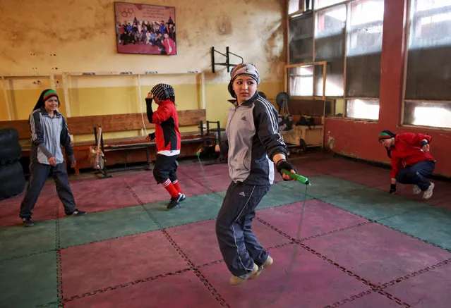 In this Wednesday, March, 5, 2014 photo, an Afghan female boxer, center, jumps rope during a practice session at the Kabul Stadium boxing club. The sportswomen share a camaraderie, laughing and teasing each other until the serious business of training begins. (Photo by Massoud Hossaini/AP Photo)