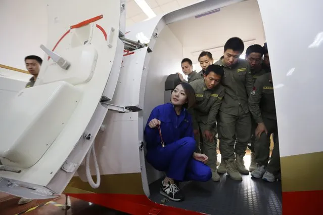 Trainees of the Tianjiao Special Guard/Security Consultant bodyguard training camp listen to an instructor about how to open a cabin door inside a scale model of a passenger jet during a course on emergency evacuation at a flight attendant training centre on the outskirts of Beijing, March 18, 2014. (Photo by Jason Lee/Reuters)