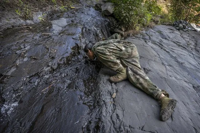 Chinese ethnic Lisu honey hunters Ma Yongde takes a drink from a stream after gathering wild cliff honey from hives in a gorge on May 31, 2019 near Mangshi, in Dehong prefecture, Yunnan province China. (Photo by Kevin Frayer/Getty Images)