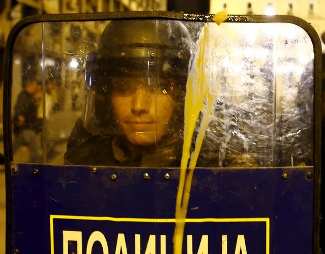A policeman hold his shield covered with egg during a protest in front of ruling party VMRO head quotes in Skopje, Macedonia, April 12, 2016. President Gjorge Ivanov ordered a halt on Tuesday to all criminal inquiries into allegations of a vast government wiretap operation, prompting the opposition to demand his resignation for a move it said amounted to a “coup d'etat”. (Photo by Ognen Teofilovski/Reuters)