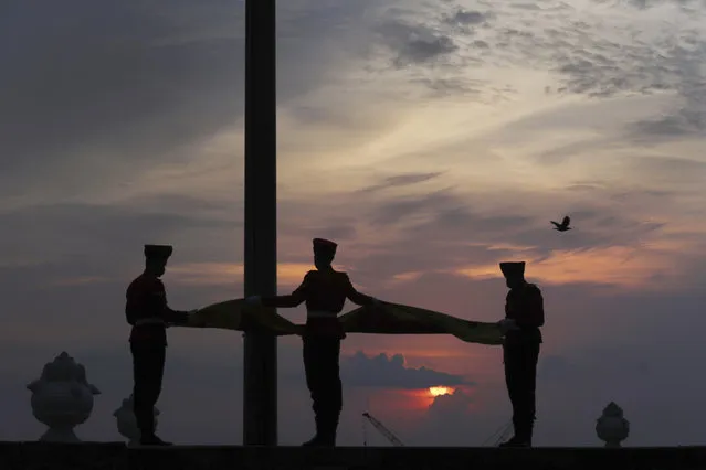 Sri Lankan Army soldiers lower the national flag as the sun sets on Sunday, in Colombo, Sri Lanka, April 28, 2019. In a rare show of unity, Sri Lankan President Maithripala Sirisena, Prime Minister Ranil Wickremesinghe and opposition leader Mahinda Rajapaksa attended the Sunday Mass in person. Their political rivalry and government dysfunction are blamed for a failure to act upon near-specific information received from foreign intelligence agencies that preceded the bombings, which targeted three churches and three luxury hotels. (Photo by Manish Swarup/AP Photo)