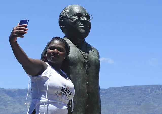 People take photos at a statue of Anglican Archbishop Desmond Tutu at the V&A Waterfront in Cape Town, South Africa, Sunday, December 26, 2021. South Africa's president says Tutu, South Africa's Nobel Peace Prize-winning activist for racial justice and LGBT rights and the retired Anglican Archbishop of Cape Town, has died at the age of 90. (Photo by AP Photo/Stringer)