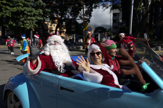 A Santa Claus rides in the back of a vehicle during the Santa Run 10K race in Caracas, Venezuela, Sunday, December 19, 2021. This is the first Santa Run since the beginning of the pandemic. (Photo by Ariana Cubillos/AP Photo)