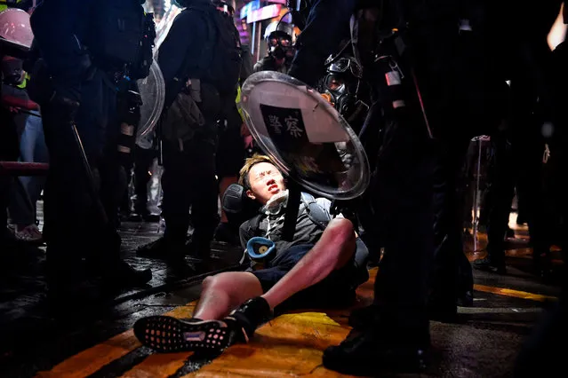 A protester is detained at Causeway Bay in Hong Kong on August 31, 2019, in the latest opposition to a planned extradition law that has since morphed into a wider call for democratic rights in the semi-autonomous city. Chaos engulfed Hong Kong's financial heart on August 31 as police fired tear gas and water cannon at petrol bomb-throwing protesters, who defied a ban on rallying – and mounting threats from China – to take to the streets for a 13th straight weekend. (Photo by Lillian Suwanrumpha/AFP Photo)