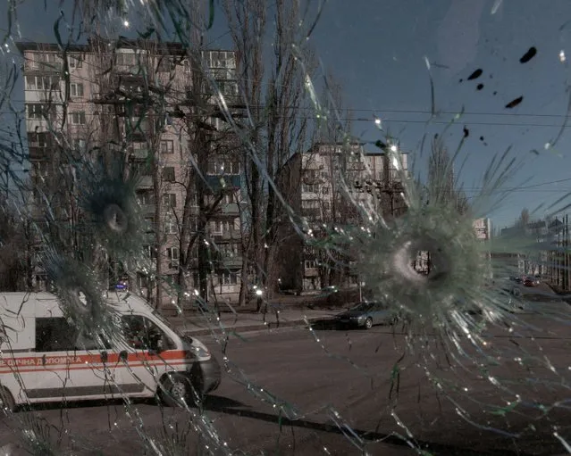 An ambulance is seen through the damaged window of a vehicle hit by bullets, as Russia's invasion of Ukraine continues, in Kyiv, Ukraine February 28, 2022. (Photo by Jedrzej Nowicki/Agencja Wyborcza.pl via Reuters)