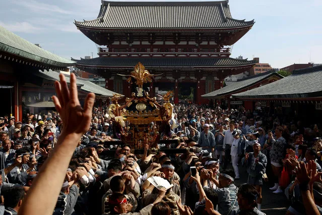 People carry a portable shrine, a Mikoshi, into the precincts of the Senso-ji Temple during the Sanja festival in Tokyo's Asakusa district, Japan, May 15, 2016. (Photo by Thomas Peter/Reuters)