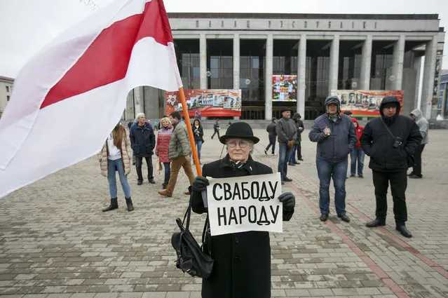 A protester holds a poster reading “Freedom for the people” and an old Belarus flag, a symbol of protest, during an opposition rally in Minsk, Belarus, Monday, May 1, 2017. The protesters marched through central Minsk calling for the government to step down and for free elections to be held. (Photo by AP Photo/Stringer)