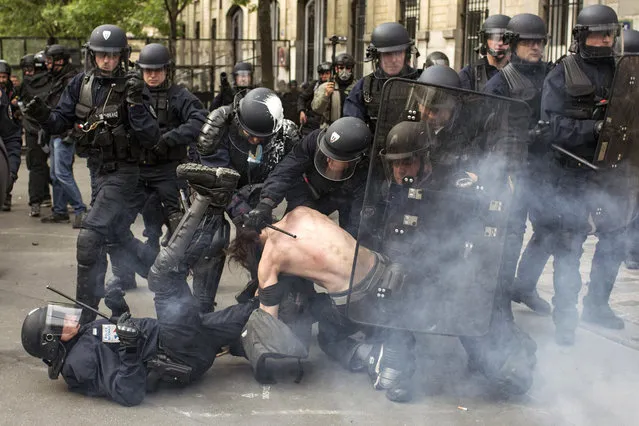Riot police officers detain a man during a demonstration against a labor law bill, Thursday, May 19, 2016 in Paris. France is facing tense weeks of strikes and other union actions against the law, allowing longer workdays and easier layoffs, and which has met fierce resistance in Parliament and in the streets. (Photo by Laurent Cirpriani/AP Photo)
