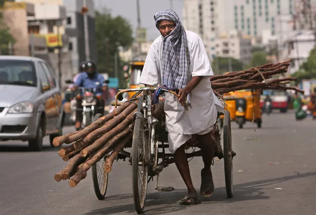 A laborer covers himself with a cloth to protect from the sun as he pulls a rickshaw carrying wooden logs on a hot summer afternoon in Hyderabad, India, Friday, May 20, 2016. (Photo by Mahesh Kumar A./AP Photo)