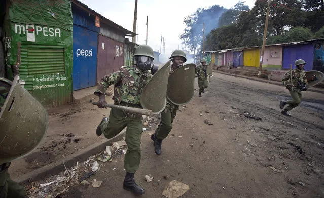 Kenyan police charge as they engage in running battles between police firing tear gas and protesters throwing rocks, in the Kibera slum of Nairobi, Kenya Monday, May 23, 2016. (Photo by Ben Curtis/AP Photo)