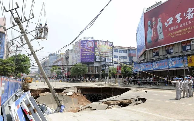 Workers try to restore a utility pole after a road collapsed in Dingyuan county, Anhui province, July 13, 2015. The caved-in area is around 100 square metres (1,076 square ft.) and three people were injured in the incident, according to local media. (Photo by Reuters/Stringer)