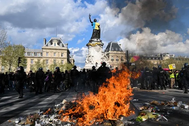 Police officers behind a fire of burning trash during a “Look up” march, to call on the presidential candidates to take into account the climate emergency, which protesters say is largely absent from campaign, in Paris on April 9, 2022. France prepares for the first round of presidential elections to be held on April 10, 2022. (Photo by Emmanuel Dunand/AFP Photo)
