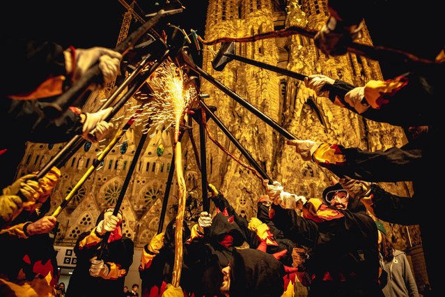 Fire runners in devil costumes gather to enlighten their stick mounted firecrackers during the “Correfocs” at the “Fiesta Major” of the Sagrada Familia in Barcelona, Spain on April 15, 2023. (Photo by Matthias Oesterle/Alamy Live News)