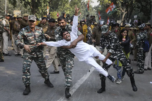 Indian paramilitary soldiers detain a Congress party supporter during a protest against the withdrawal of Special Protection Group (SPG) cover to party president Sonia Gandhi, her children Rahul Gandhi and Priyanka Vadra and former prime minister Manmohan Singh, in New Delhi, India, Wednesday, November 20, 2019. The move to lift off the SPG security, an elite force that protects prime ministers and their immediate families, led to sharp reactions from the Congress, which accused the government of personal vendetta. (Photo by Altaf Qadri/AP Photo)