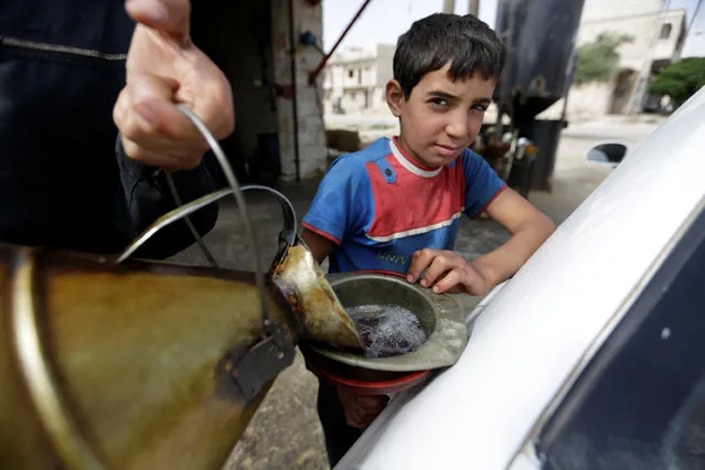 A boy holds a funnel while refuelling a vehicle, in the rebel-controlled area of Maaret al-Numan town in Idlib province, Syria May 26, 2016. (Photo by Khalil Ashawi/Reuters)