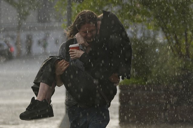 A man carries a woman during a heavy rain in Moscow, Russia, on Monday, August 5, 2024. (Photo by Pavel Bednyakov/AP Photo)