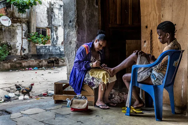 Ceia gives Alexandra a pedicure in the grounds of the building. (Photo by Tariq Zaidi/The Guardian)