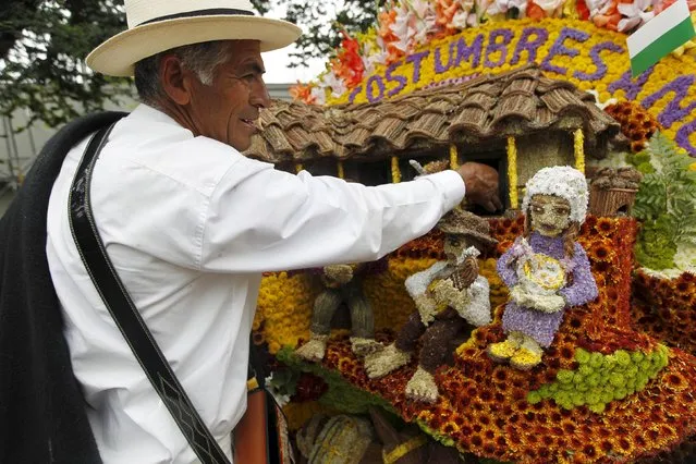 A flower grower, known as a silletero, looks at flower arrangements as he participates in the annual flower parade in Medellin, Colombia, August 9, 2015. (Photo by Fredy Builes/Reuters)