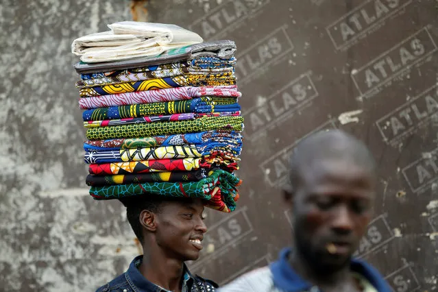 A man selling unsewn fabrics locally known as "Ankara" walks past through a street at Agege district in Lagos, Nigeria June 22, 2016. (Photo by Akintunde Akinleye/Reuters)