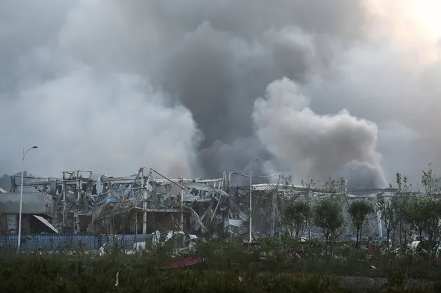 Smoke billows from the site of an explosion in Tianjin, in northern China, on August 13, 2015. A series of massive explosions at a warehouse in the northern Chinese port city of Tianjin killed 13 people, state media reported on August 13, as witnesses described a fireball produced by the blasts ripping through the night sky. (Photo by Greg Baker/AFP Photo)