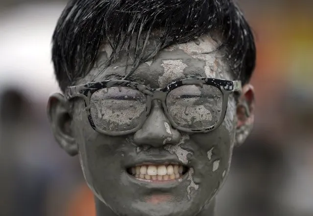A tourist poses for photographs as he plays in the mud during the Boryeong Mud Festival at Daecheon beach in Boryeong July 18, 2014. About 2 to 3 million domestic and international tourists visit the beach during the annual mud festival, according to the festival organisers. (Photo by Kim Hong-Ji/Reuters)