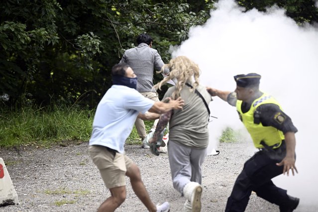 A counter-demonstrator extinguishes a Quran on fire outside the Iranian embassy, in Stockholm, Friday, August 18, 2023. A woman with a fire extinguisher on Friday raced toward the man who set fire to a Quran outside the Iranian Embassy in Stockholm but was stopped by plain clothes officers. Swedish media said the woman, who was not identified, was detained, suspected of disturbing public order and violence against a police officer. Salwan Momika, the protester, was not injured. (Photo by Fredrik Sandberg/TT News Agency via AP Photo)