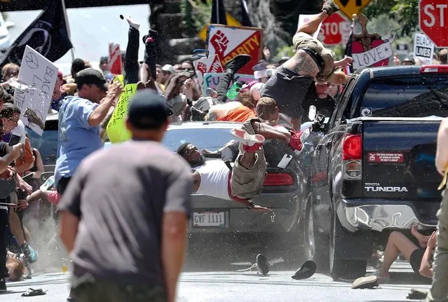 People fly into the air as a vehicle drives into a group of protesters demonstrating against a white nationalist rally in Charlottesville, Va., Saturday, August 12, 2017. The nationalists were holding the rally to protest plans by the city of Charlottesville to remove a statue of Confederate Gen. Robert E. Lee. There were several hundred protesters marching in a long line when the car drove into a group of them. (Photo by Ryan M. Kelly/The Daily Progress via AP Photo)