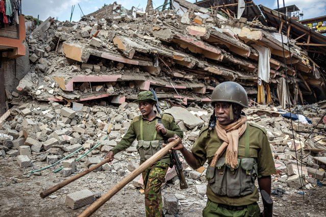 Kenya Police officers give instructions to bystanders to evacuate the area next to a collapsed residential building at Kahawa West residential area in Nairobi on October 20, 2024. Response teams were responding to a building collapse in Nairobi, where people are feared trapped despite a vacation notice. (Photo by Luis Tato/AFP Photo)