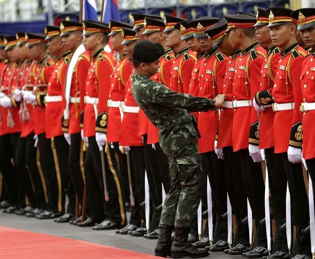 A Thai army officer adjusts the belt of a member of the honor guard in preparation for the arrival of Laos Prime Minister Thongloun Sisoulith at the government house in Bangkok, Thailand, Wednesday, July 6, 2016. Thongloun is on a two-day visit to Thailand. (Photo by Sakchai Lalit/AP Photo)