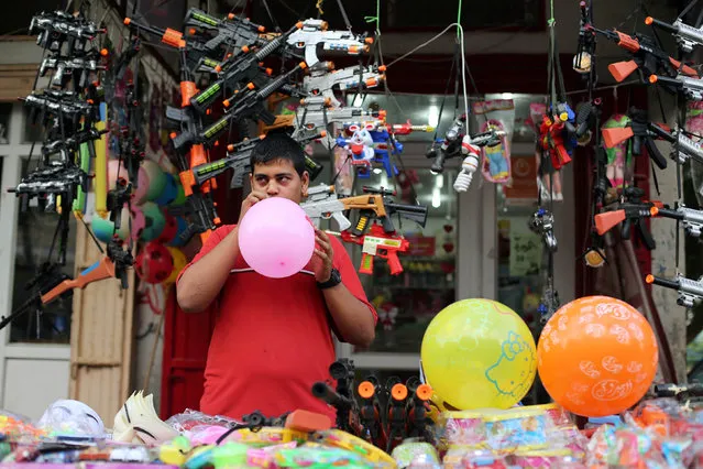 A Palestinian vendor blows a balloon as he sells toys in a market ahead of the Eid al-Fitr holiday marking the end of Ramadan, in the central Gaza Strip July 4, 2016. (Photo by Ibraheem Abu Mustafa/Reuters)