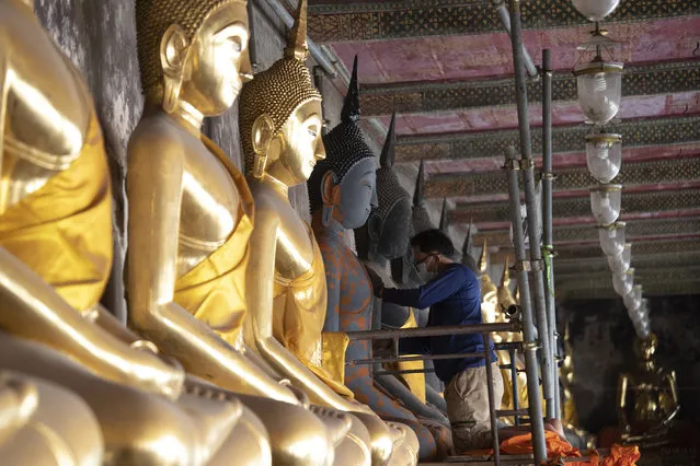 A Thai worker wears a face mask to protect from a new coronavirus as he repairs Buddha statues at Suthat Temple in Bangkok, Thailand, Tuesday, March 10, 2020. For most people, the new coronavirus causes only mild or moderate symptoms, such as fever and cough. For some, especially older adults and people with existing health problems, it can cause more severe illness, including pneumonia. (Photo by Sakchai Lalit/AP Photo)