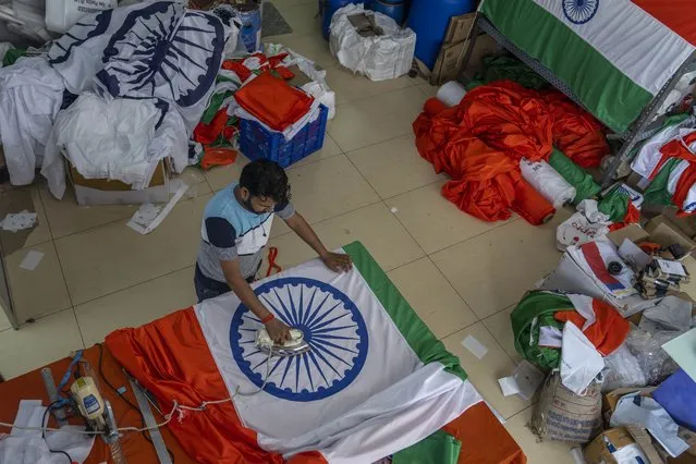 A worker irons an India flag at a workshop ahead of India's independence day in Mumbai, India, Tuesday, August 2, 2022. India will celebrate its Independence Day on Aug. 15. (Photo by Rafiq Maqbool/AP Photo)