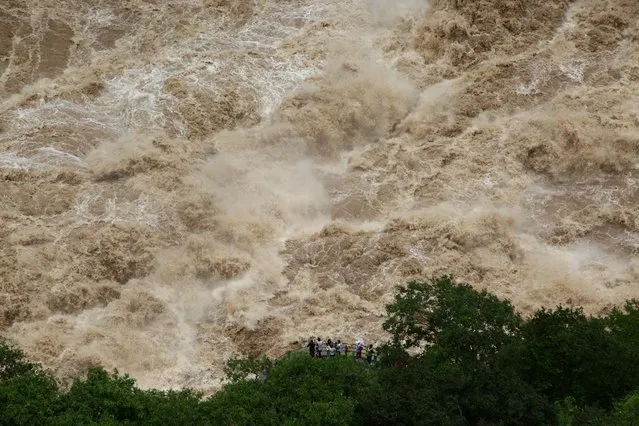 People watch the flooded Jinsha River at a sightseeing platform of Tiger Leaping Gorge, in Diqing, Yunnan Province, China, July 15, 2016. (Photo by Reuters/Stringer)