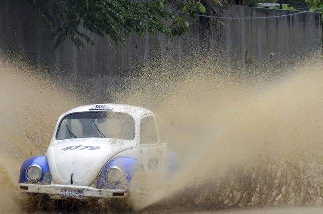 A taxi speeds along a rain flooded street in Acapulco, Guerrero state, Mexico, Thursday, September14, 2017. Hurricane Max hit Mexico's southern Pacific coast as a Category 1 storm Thursday, and was expected to move inland into Guerrero state, a region that includes the resort city of Acapulco. (Photo by Bernandino Hernandez/AP Photo)