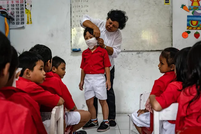 A teacher shows students how to use a mask made from tissue at the Cinta Bangsa kindergarten as Indonesia reports two cases of COVID-19 on March 4, 2020 in Yogyakarta, Indonesia. Two women in Indonesia have tested positive for Coronavirus after having had contact with a Japanese national and are being treated at Sulianti Saroso infectious diseases hospital in Jakarta. The news comes as heath experts express concerns that cases are going unreported in Indonesia, a country that has close economic ties to China including being one of the top ten destinations for travellers from Wuhan, the epicentre of the epidemic. (Photo by Ulet Ifansasti/Getty Images)