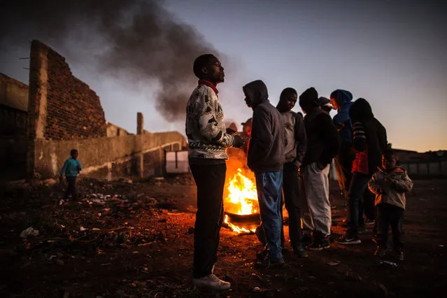 Residents of the Kliptown section of Soweto gather next to burning tyres during a service delivery demonstration on July 27, 2016 ahead of August 3rd municipal elections. (Photo by Marco Longari/AFP Photo)