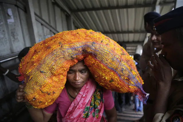 A woman carries a sack of flowers on her head as she walks across a pedestrian bridge where a stampede took place at the Elphinstone station, in Mumbai, India, Friday, September 29, 2017. (Photo by Rafiq Maqbool/AP Photo)