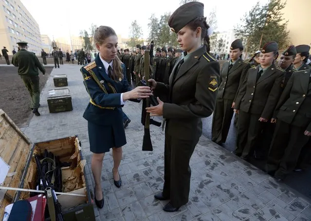 A first year cadet of the Military University of Communication is handed her weapon before an oath-taking ceremony in St.Petersburg September 6, 2014. (Photo by Alexander Demianchuk/Reuters)