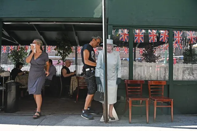 A woman walks past a life-sized cut-out of Britain's Queen Elizabeth II outside the British owned business of Tea & Sympathy in Manhattan's Greenwich Village in New York on September 9, 2022. Queen Elizabeth II, the longest-serving monarch in British history and an icon instantly recognisable to billions of people around the world, died at her Scottish Highland retreat on September 8, at the age of 96. (Photo by Andrea Renault/AFP Photo)