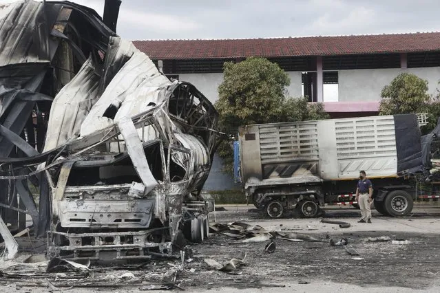 A Thai officer stands beside the burnt down oil tanker at a gas station in Pattani province, southern Thailand, Wednesday, August 17, 2022. A wave of arson and bombing attacks overnight hit Thailand’s southernmost provinces, which for almost two decades have been the scene of an active Muslim separatist insurgency, officials said Wednesday. (Photo by Sumeth Panpetch/AP Photo)