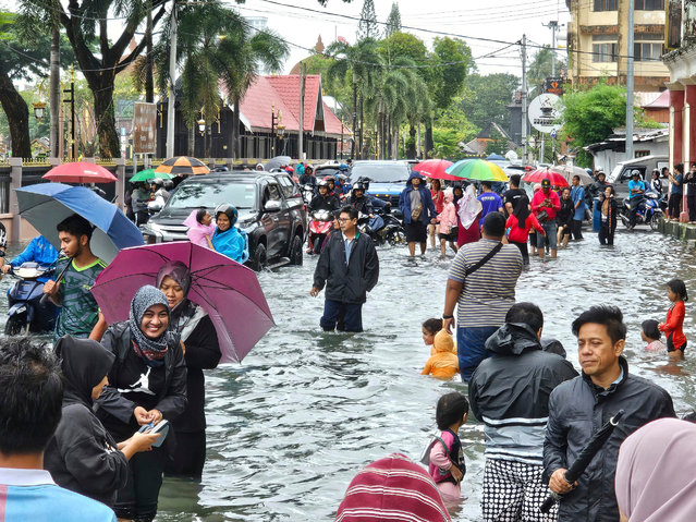 Residents walk on a flooded street after heavy monsoon rains in downtown Kota Bharu, Kelantan, Malaysia, Friday, November 29, 2024. (Photo by Loo Kok Chong/AP Photo)